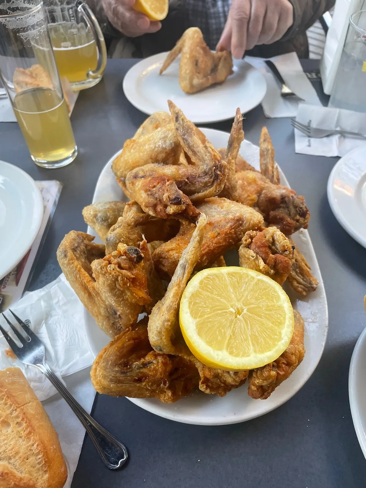 Fuente de alitas de pollo fritas con una rodaja de limón, junto a una jarra de cerveza