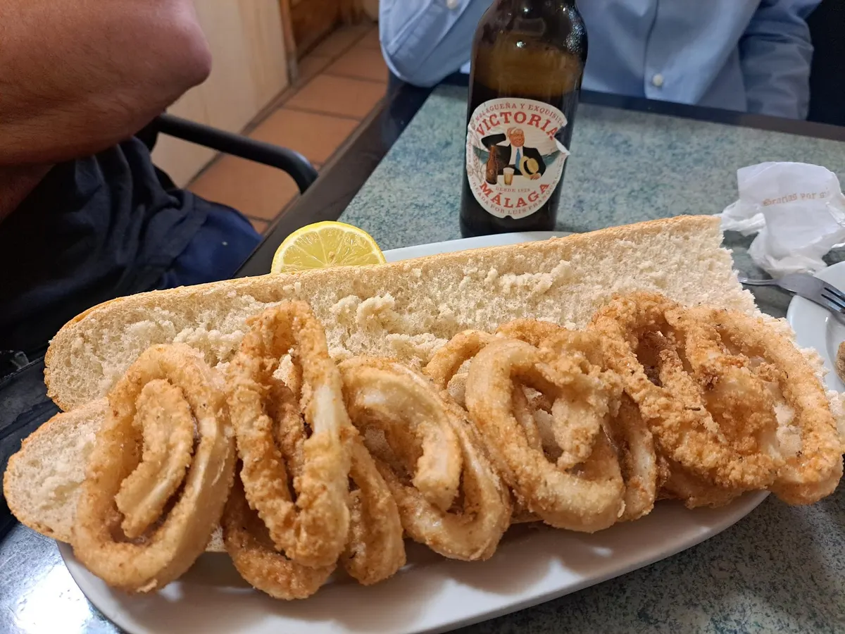 Bocadillo de calamares abierto, con las anillas rebozadas sobre el pan y medio limón