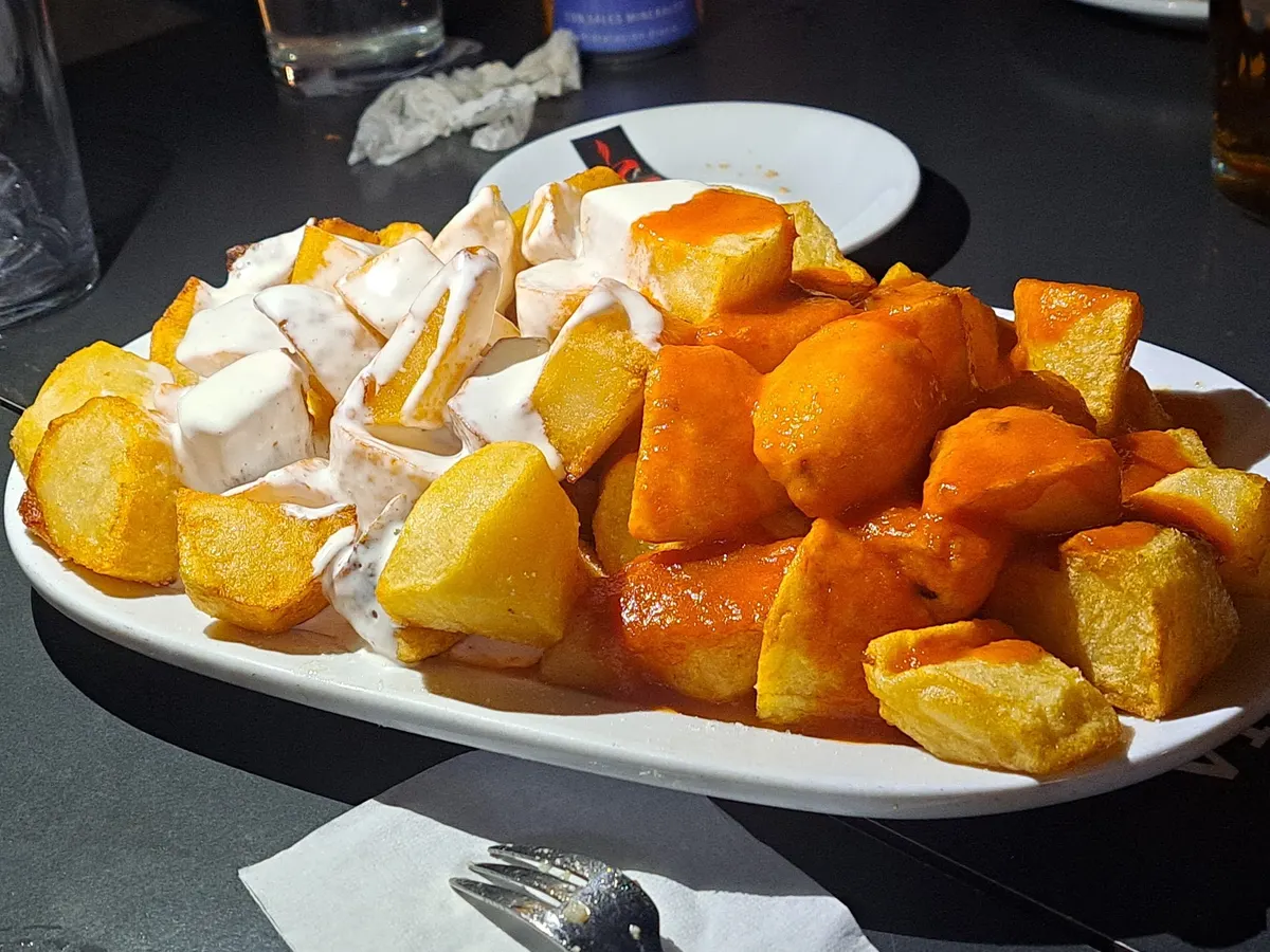 Fuente de patatas fritas en dados, mitad con salsa brava y mitad con ali-oli